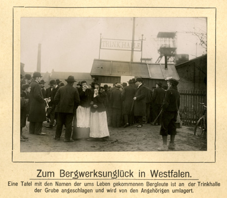 Eine Tafel mit den Namen der ums Leben gekommenen Bergleute wird von den Angehörigen umlagert; November 1908